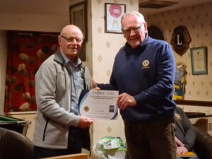 A man handing a certificut to another man for effort and generosity of spirt